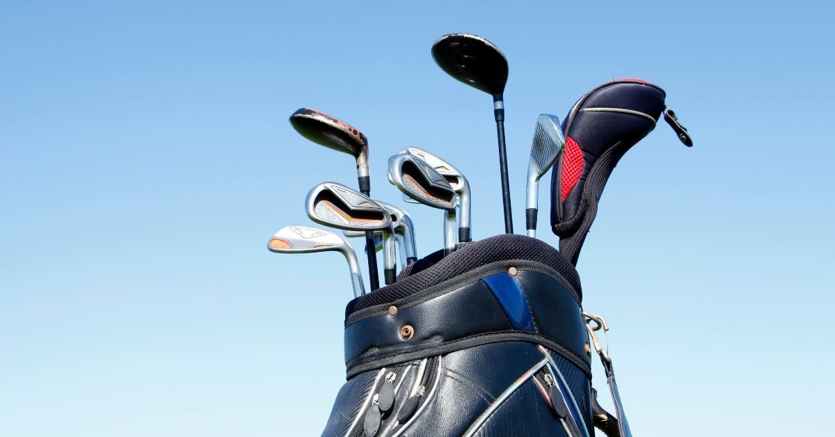 A number of golf clubs in a bag behind a blue sky