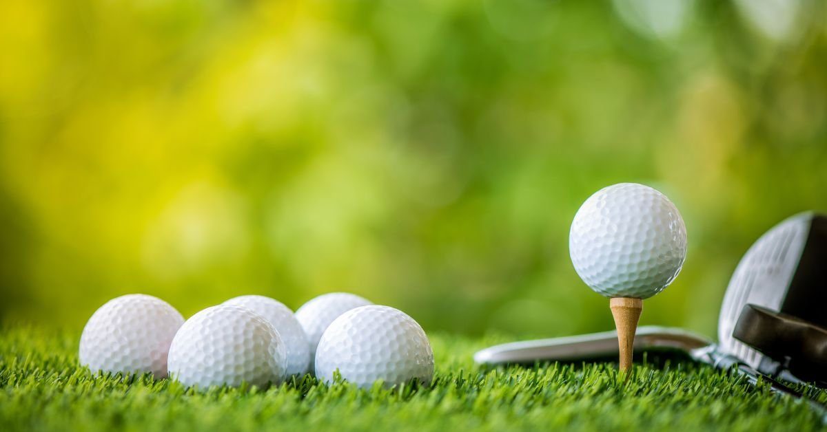 A few golf balls lying next to a golf club